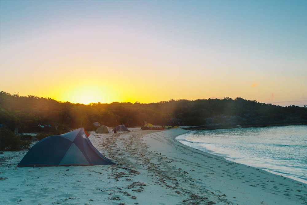 Sunset sea kayak expedition camping on beach