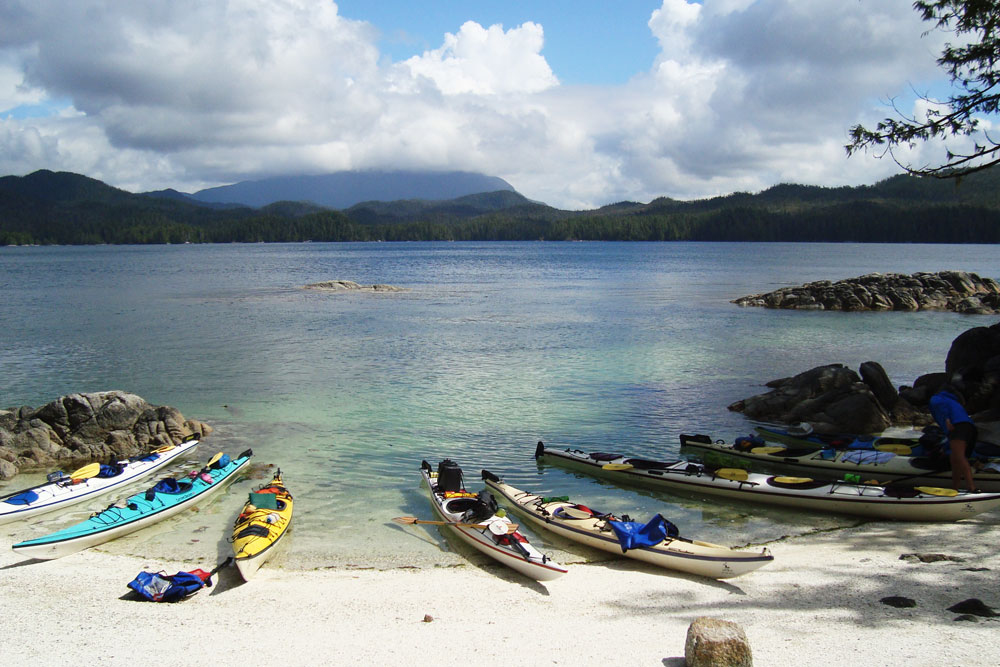 Ocean kayaks along a sandy beach in the Great Bear Rainforest.