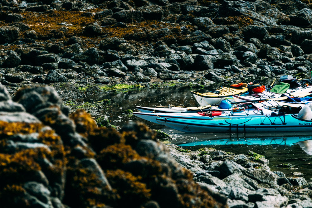 Ocean kayaks in a rocky kelp covered cove along the BC coast.