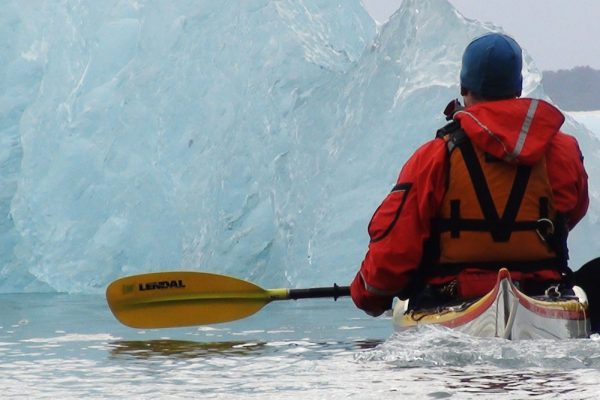 A person kayaking next to an iceberg in Chile
