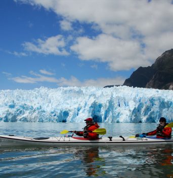 Kayakers paddling past a large glacier in Chile