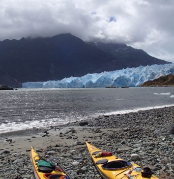 Kayaks on a beach across from a large glacier in Chile