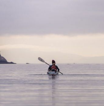 Lone sea kayaker paddling on an overcast day