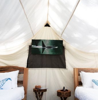 Canvas tent interior with rustic furniture and beds.