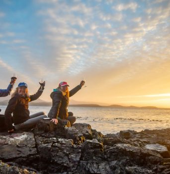 Three guest toasting to the day at sunset