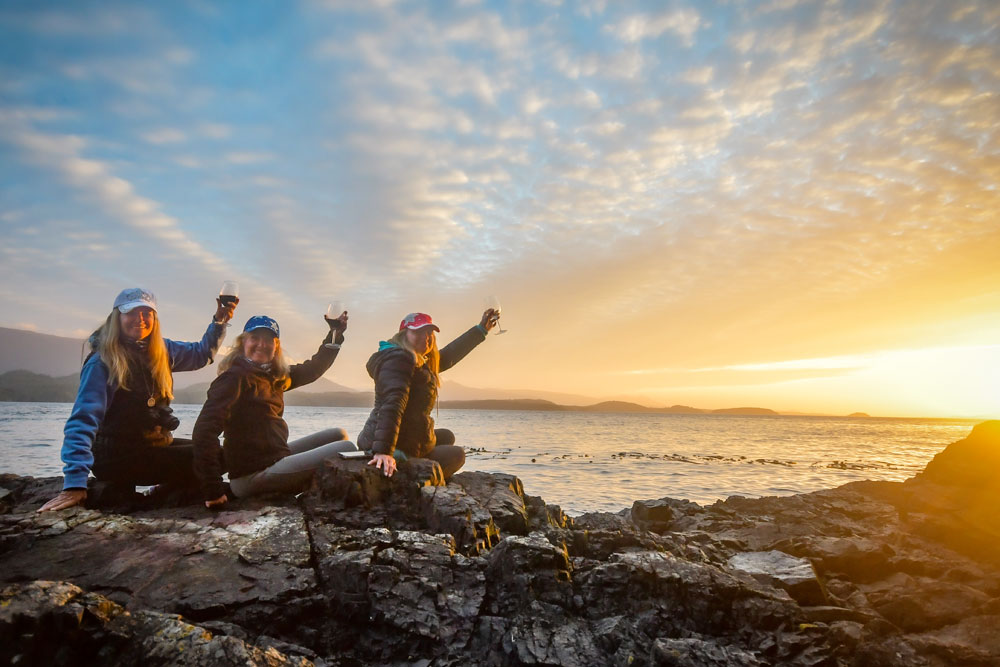 Guests enjoying drinks by the water at sunset