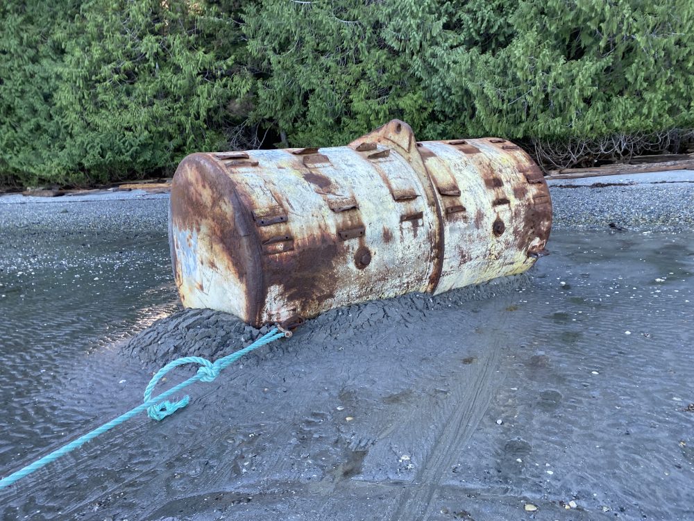 Large steel mooring float getting pulled off beach