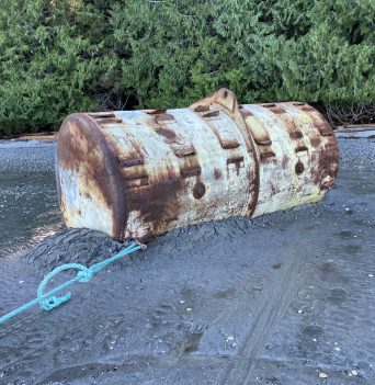 Large steel mooring float getting pulled off beach