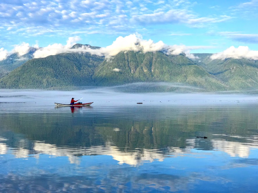 Person Kayaking with the Mountain & Clouds in the Background
