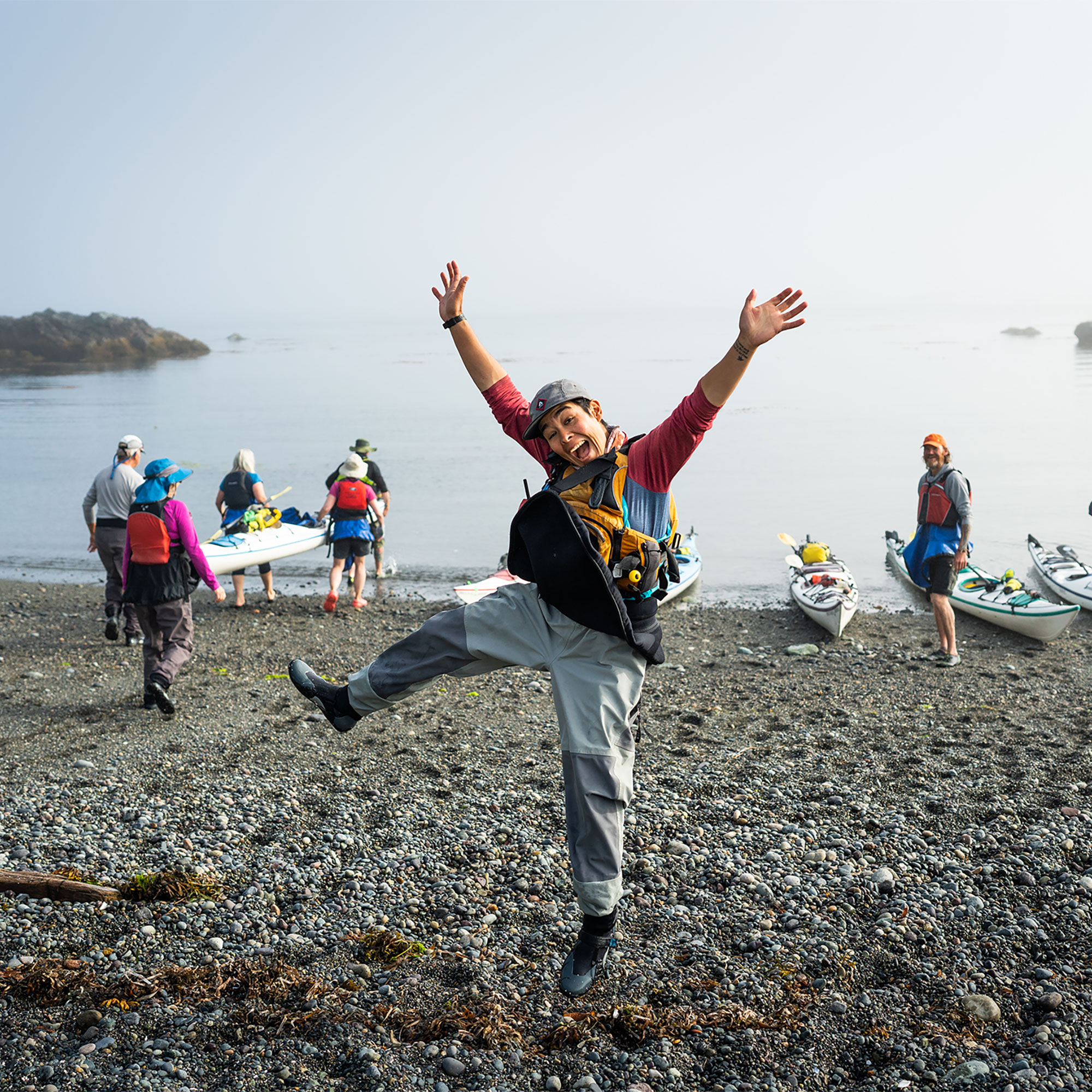 Happy Kayak Guide Jumping with Hands in Air with Coastal BC Backdrop