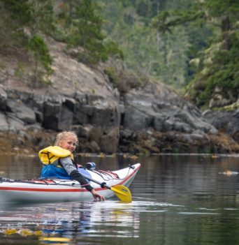 A happy kid kayaking on the BC coast