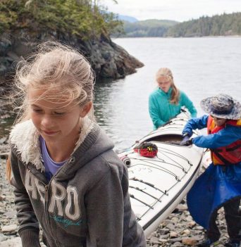 A group of kids carrying sea kayak