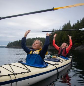 Kids throwing paddle above their head in the Johnstone Strait