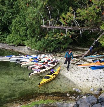 Kayaker docking boats on shore