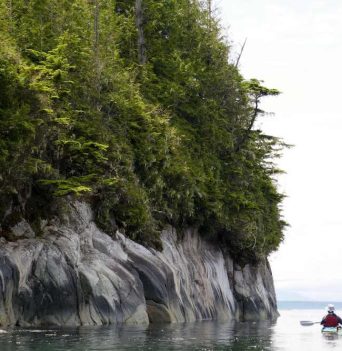 Sea kayakers paddling along rocky bluffs