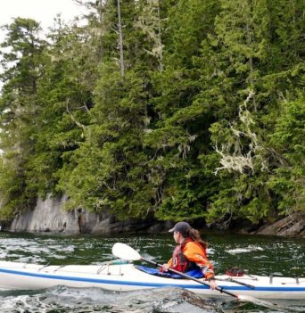 Kayaker along rocky bluffs of the Johnstone Strait
