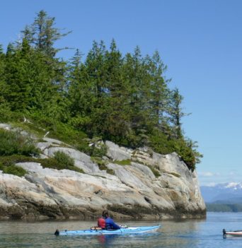 Two ocean kayaker paddling along rocky bluffs