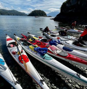 A group of kayaks on the shore along the BC Coast
