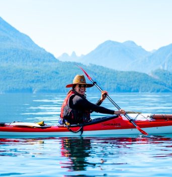 Happy kayaker on a sunny day paddling with BC coastal mountains in background