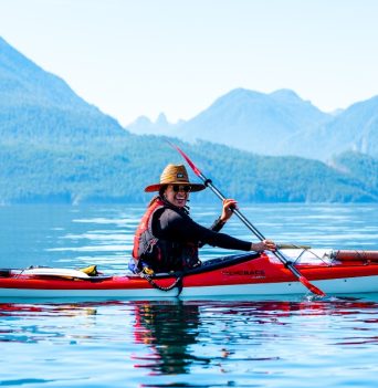 Happy Kayaker on sunny day paddling with BC coastal mountains in background
