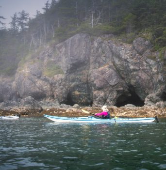 Ocean kayakers paddling rocky caves