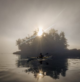 Kayaker paddling in front of hazy island