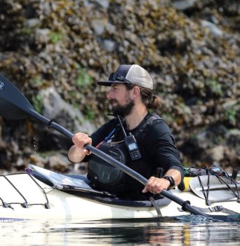Kayak guide in front of rocky bluffs