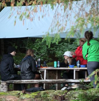 Group dining under tarp on rustic picnic table