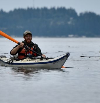 Kayaker paddling along shore of Johnstone Strait