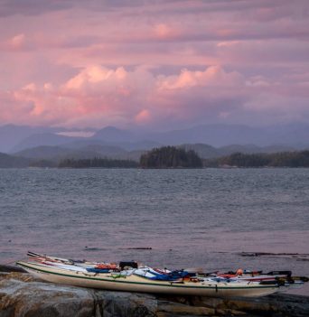 Kayaks on the shore with the sunset of coastal BC