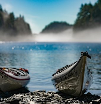 Two kayaks on shore with marine fog layer on sunny day