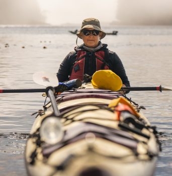 Person kayaking in calm hazy BC coastal waters