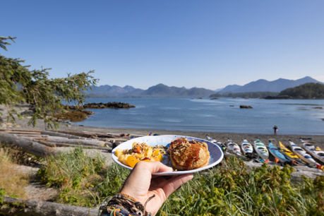 Plate of food being held by above a beach of kayaks on the west coast
