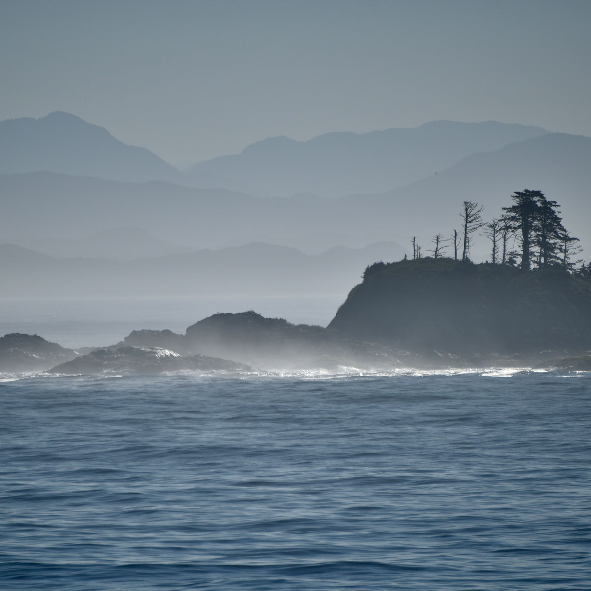 Blue Coastal BC Landscape with Ocean, Rocks and Layered Mountains