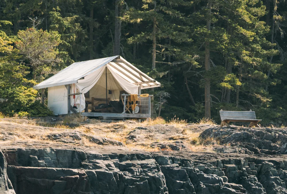 A cliffside white canvas tent at the Johnstone Strait Glamping camp