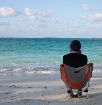 A person sitting in a chair at the beach looking at the ocean