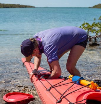 Person putting their personal gear inside of a plastic kayak