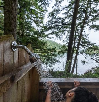 Woman in an outdoor shower overlooking the ocean
