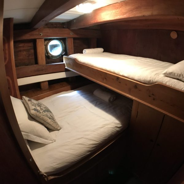 Two beds with white linens in a Chilean expedition yacht