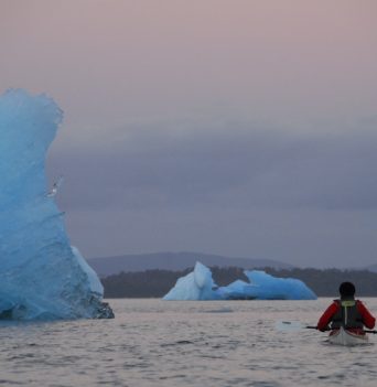 A kayaker paddling next to a large glacier in Chile