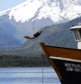 A man diving off of a boat into the sea in Chile