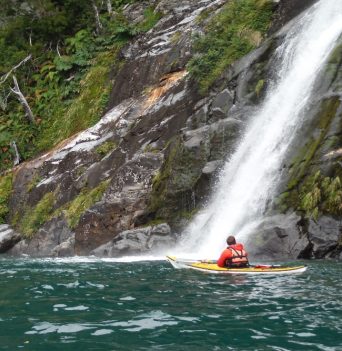 A kayaker floating in front of a waterfall in Chile