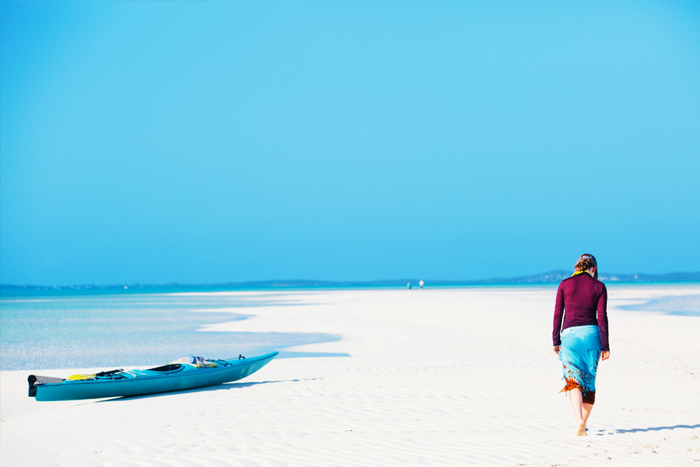 A person walking on a white sand beach in the Bahamas