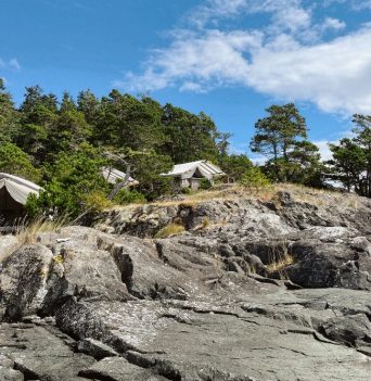 A group of cotton canvas tents on a rocky bluff in the Johnstone Strait