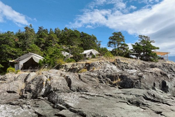 A group of cotton canvas tents on a rocky bluff in the Johnstone Strait