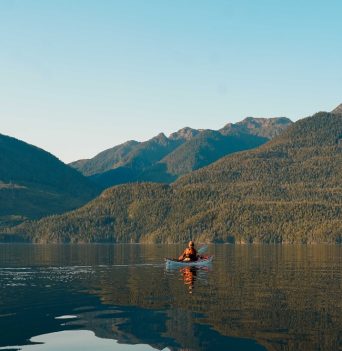 A kayaker paddling through open waters in coastal BC