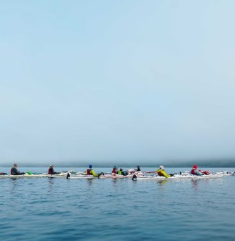A group of kayakers resting in open water on a foggy morning