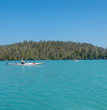 A kayaker paddling in turquoise waters