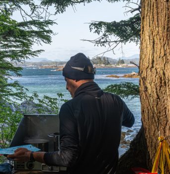 A guide cooking dinner with the ocean in the background