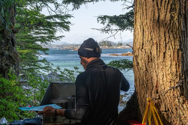 A guide cooking dinner with the ocean in the background